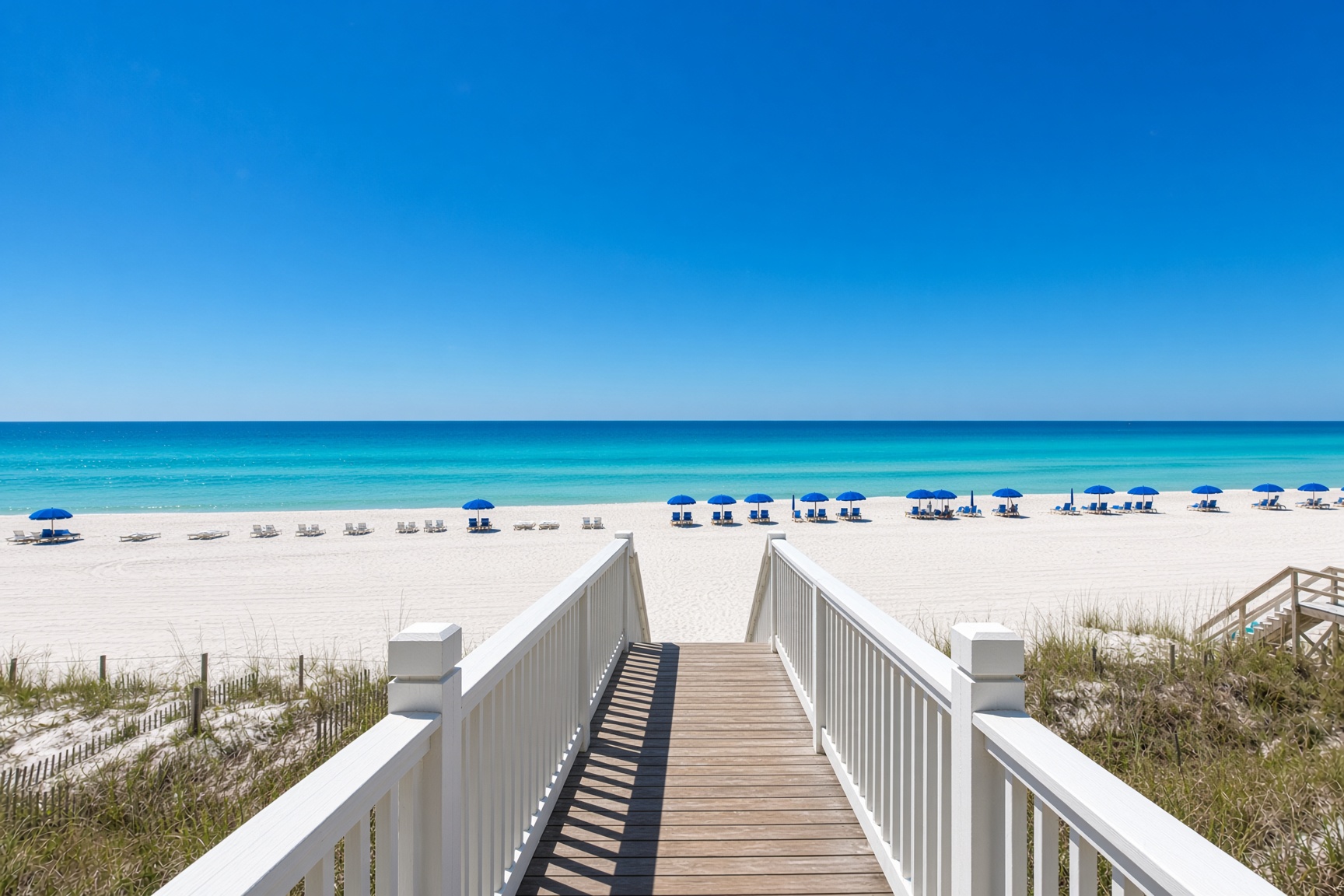 Boardwalk to the gulf with blue umbrellas