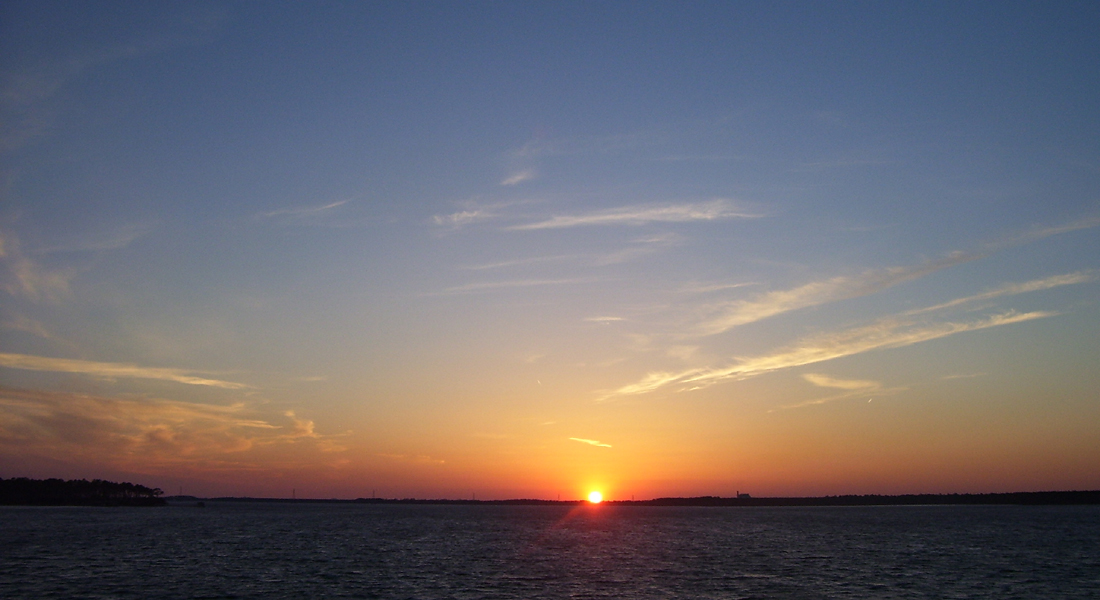 Sunset over calm bay water